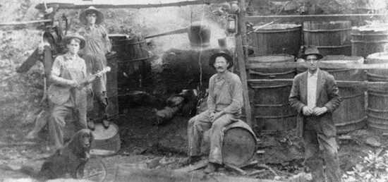 Hosea Thomas' still workers in Endicott, (Franklin County) Virginia, 1915. The Martin, Rake, and Thomas families trace their origins to Ireland where local residents learned to make liquor (known in Ireland as "potchin") to supplement farm income. Photo courtesy of the Blue Ridge Institute of Ferrum College. Hosea Thomas' still workers in Endicott, (Franklin County) Virginia, 1915. The Martin, Rake, and Thomas families trace their origins to Ireland where local residents learned to make liquor (known in Ireland as "potchin") to supplement farm income. Photo courtesy of the Blue Ridge Institute of Ferrum College.