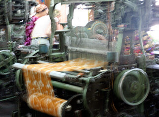 Women workers tending Draper automatic looms originally used in the American South. Margilan, Uzbekistan, 2006. The wooden floor of the weave room shook constantly; the noise was deafening.