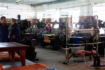 Mary E. Frederickson, As in the mills of the New South, male supervisors oversee the Margilan weave room, Uzbekistan, 2006.