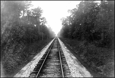 The N.Y., P. & N. was built down the high, dry, and sparsely populated spine of the peninsula. Seeing little evidence of human activity, early travelers felt "walled in" by the pines. Notice the oyster-shell ballast.