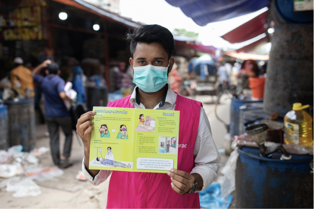 A project volunteer showing a Covid-19 info card, Bangladesh.
