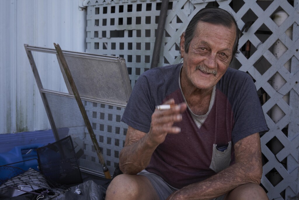 A man holding the cigarette and smiling. How long can he make it before the wrecking ball comes for his entire trailer park? And when it’s gone, where will he go? The lattice here serves more like a net that the subject is caught in–that has ensnared all of us. His expression, though, speaks to a consanguinity, a softness that belies the other ravages the man has endured. 
